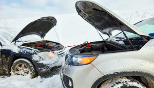 two cars in the snow with jumper cables